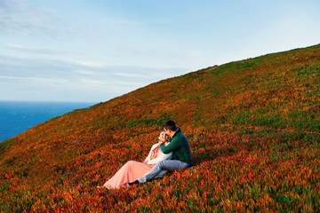 Wall Mural - happy couple in love sit on the grass in the arms of each other.