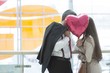 © moodboard - Man and woman kiss behind heart shaped balloon