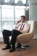 © moodboard - Businessman in arm chair working on laptop on the phone