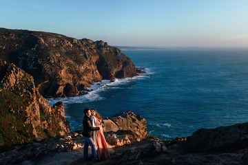 Wall Mural - a couple in love embracing each other on a rocky coast of the oc