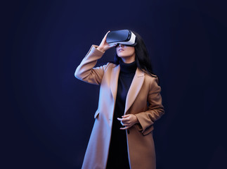Wall Mural - beautiful woman in fashionable clothes over dark background. girl in glasses of virtual reality. aug