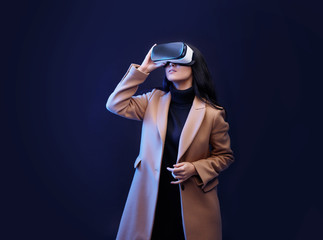 Wall Mural - beautiful woman in fashionable clothes over dark background. girl in glasses of virtual reality. aug