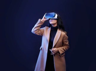 Wall Mural - beautiful woman in fashionable clothes over dark background. girl in glasses of virtual reality. aug