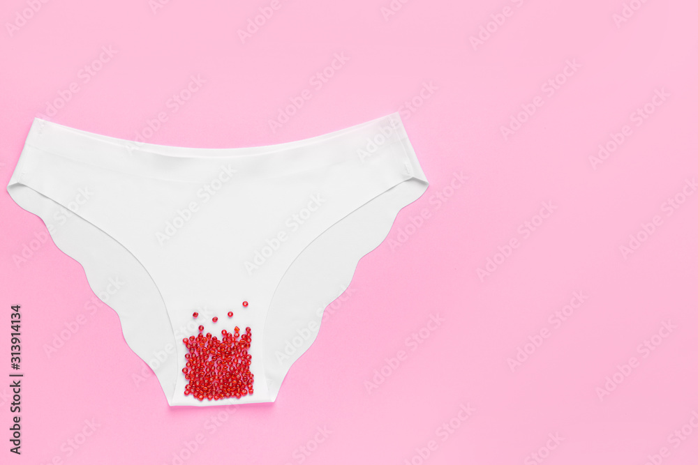 Female panties with red beads on color background. Menstruation concept