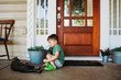 © Cavan Images - Young boy sitting outside front door petting short hair cat