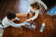 © Cavan Images - Young brother and sister picking beads to making bracelets at home