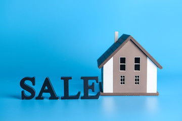 Model of house with word SALE on color background. Concept of real estate