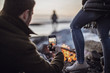 © Cavan Images - A man takes a picture of a campfire with his cell phone or smartphone
