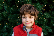 Portrait Of A Happy, Curly-haired Boy In Front Of A Christmas Tree