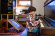 © Cavan Images - side view of a child sitting in window light practicing piano