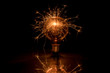 canvas print picture - Electric tungsten lightbulb on a black background emitting sparks