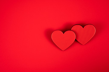 Two red hearts representing the love of two on a red background for Valentine's Day, wedding and other holidays, view from the top.