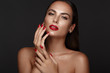 © Kobrinphoto - Beautiful girl with a classic make-up and red nails. Manicure design. Beauty face.