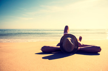 Wall Mural - Unrecognizable man in vintage beach hat relaxing on the smooth sand of an empty beach