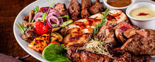 Turkish Cuisine. Assorted Different Meat On The Grill, Lamb, Chicken, Pork With Grilled Vegetables. Serving Dishes In A Restaurant On A White Plate. Background Image, Copy Space