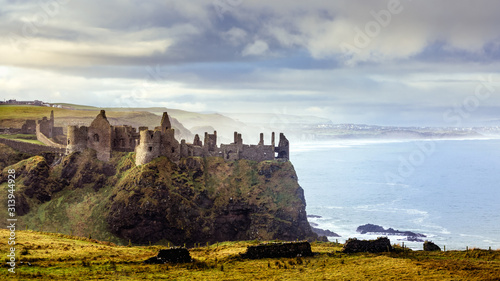 Photographie Ruined medieval Dunluce Castle on the cliff dramatic sky