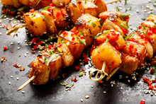 Grilled Skewers With Pineapple Fruit And Chicken Meat  Sprinkled With Sesame Seeds, Chilli Pepper And Fresh Herbs On A Black Background, Close-up  Fruit And Meat Skewers