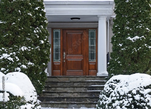 Fotografía Elegant wooden front door of house with snow covered shrubbery