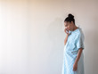 © Joseph Kirsch - A young postpartum mixed race African American woman wearing a hospital gown or robe hunches over and looks down as she dries her eyes from tears of sadness or depression from a loss.