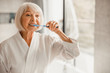 © Yakobchuk Olena - Elderly woman in bathrobe brushing teeth in the morning