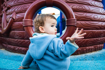 Wall Mural - A 1 year old baby girl in a park with a gesture of asking for explanations.