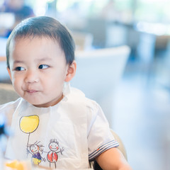 Wall Mural - Asian baby boy holding food in mouth in breakfast time.problem in kid.Asian baby boy try to talk in table kitchen.