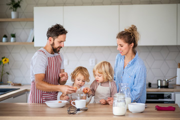 Wall Mural - Young family with two small children indoors in kitchen, cooking.