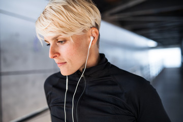 Wall Mural - A portrait of young sportswoman doing exercise outdoors, resting.