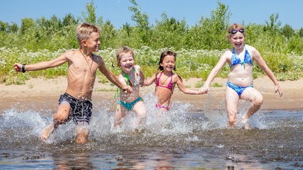 Wall Mural - group of beautiful children runs in a wig and splashes water on a summer hot sunny day