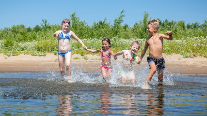 Wall Mural - group of beautiful children runs in a wig and splashes water on a summer hot sunny day