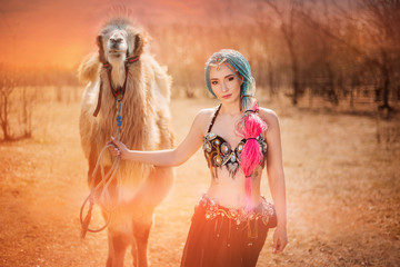 Wall Mural - Beautiful girl with multi-colored braids in oriental clothes. Princess with a camel at sunset. in desert