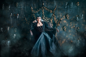 Evil Queen in a black dress. Beautiful girl in the crown sits on the throne