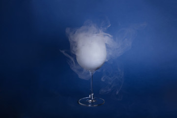 Large wine glasses with smoke on a blue background. Color of the year 2020, Classic Blue.