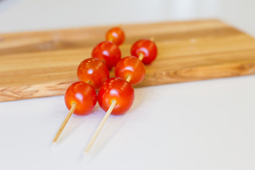 cherry tomatoes on skewers on a wooden Board, on a white background. texture. concept of fresh vegetables and healthy food. BBQ. space for text. top view of tomatoes. ripe harvest.