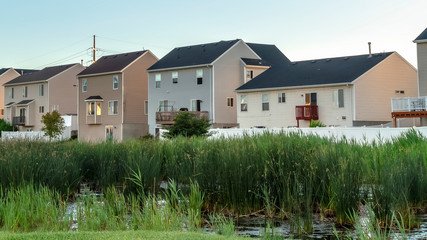 Wall Mural - Pano frame Green grasses and pond at a scenic park with houses and blue sky background