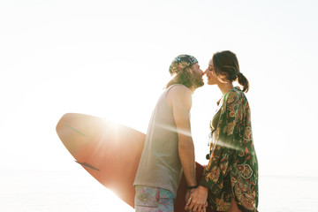 Wall Mural - Photo of nice romantic couple holding surfboard and kissing