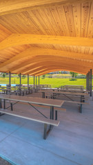 Wall Mural - Vertical frame Sunny day views at a park with pavilion and basketball court under blue sky