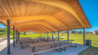 Pano Sunny day views at a park with pavilion and basketball court under blue sky