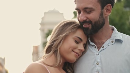 Poster - Happy lovely beautiful couple are embracing while standing at the city street, hugging