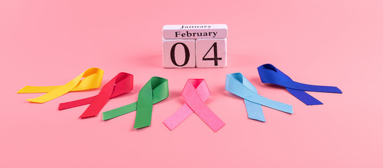 World cancer day (February 4). colorful awareness ribbons; blue, red, green, pink and yellow color on wooden background for supporting people living and illness. Healthcare and medicine concept