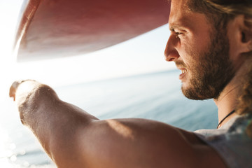 Wall Mural - Photo of pleased confident man holding surfboard and pointing finger