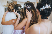 The bridesmaids and the bride straighten their hairstyles and hold on to their hair. Morning of the bride with best friends. Wedding bachelorette party. Photography, concept.
