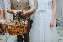 The Groom Stands Next To The Bride And Holds A Wicker Basket With Gifts And Surprises From A Bag For Guests. Wedding Ceremony, Party. Photography, Concept.
