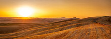 Beautiful Panoramic View Of Orange Sunset Over Rural Landscape In Tuscany With Wheat Field, Rolling Hills, Isolated Farm House And Rising Sun. Travel Destination Tuscany, Italy