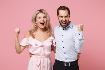 Wall Mural - Happy young couple two guy girl in party outfit celebrating posing isolated on pastel pink wall background. People lifestyle Valentine's Day Women's Day birthday holiday concept. Doing winner gesture.