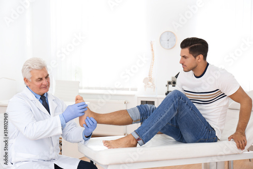 Fotografía Male orthopedist checking patient's foot in clinic