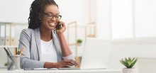Black Businesswoman Talking On Cellphone And Using Laptop In Office, Panorama