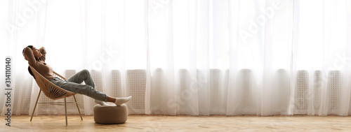 Fotografía Young Asian Girl Relaxing In Modern Wicker Chair Near Window