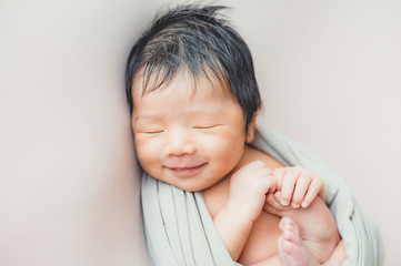 asian newborn baby sleeping in blanket on bed