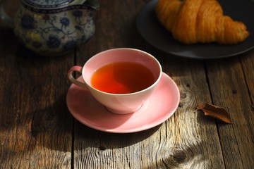 Wall Mural - Pink Cup with fragrant tea on a wooden background. Tea mood. Tea composition.